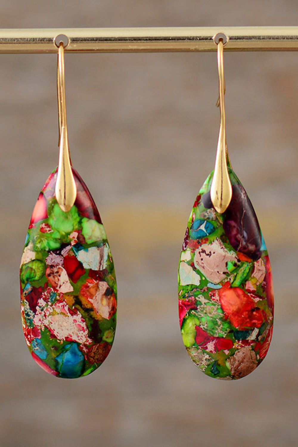 Colorful teardrop-shaped earrings with gold hooks on a blurred background