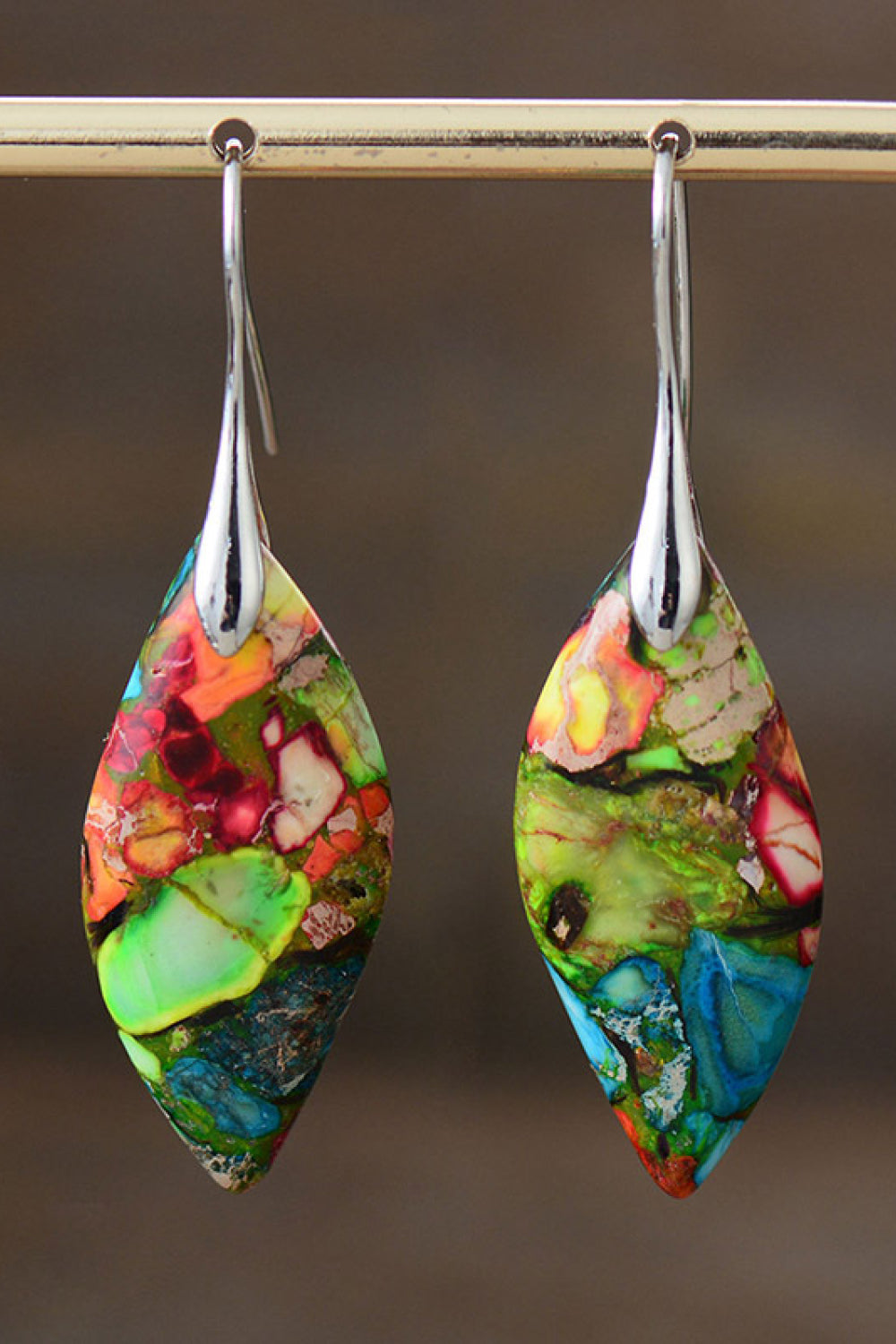 Colorful teardrop-shaped earrings with silver hooks on a dark background