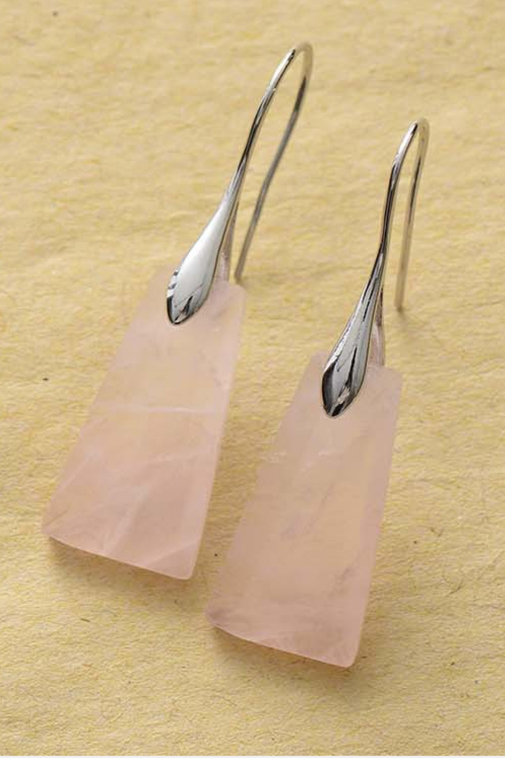 Rose quartz with silver hooks on a yellow background
